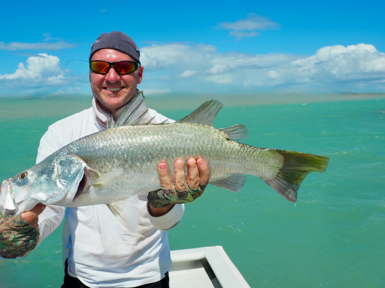 Angler with a barramundi in a mangrove creek