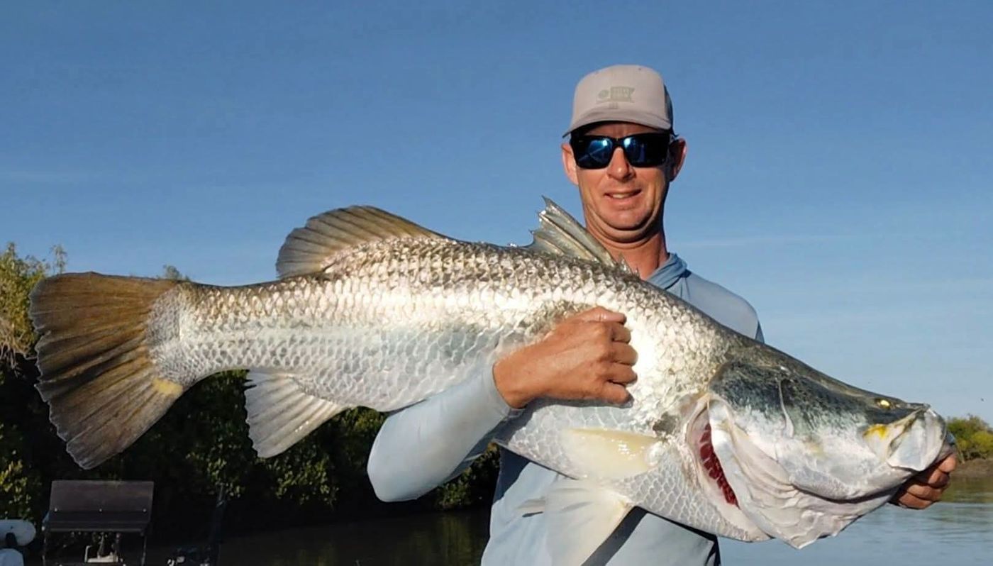 Smiling angler with a large barramundi against the mangroves