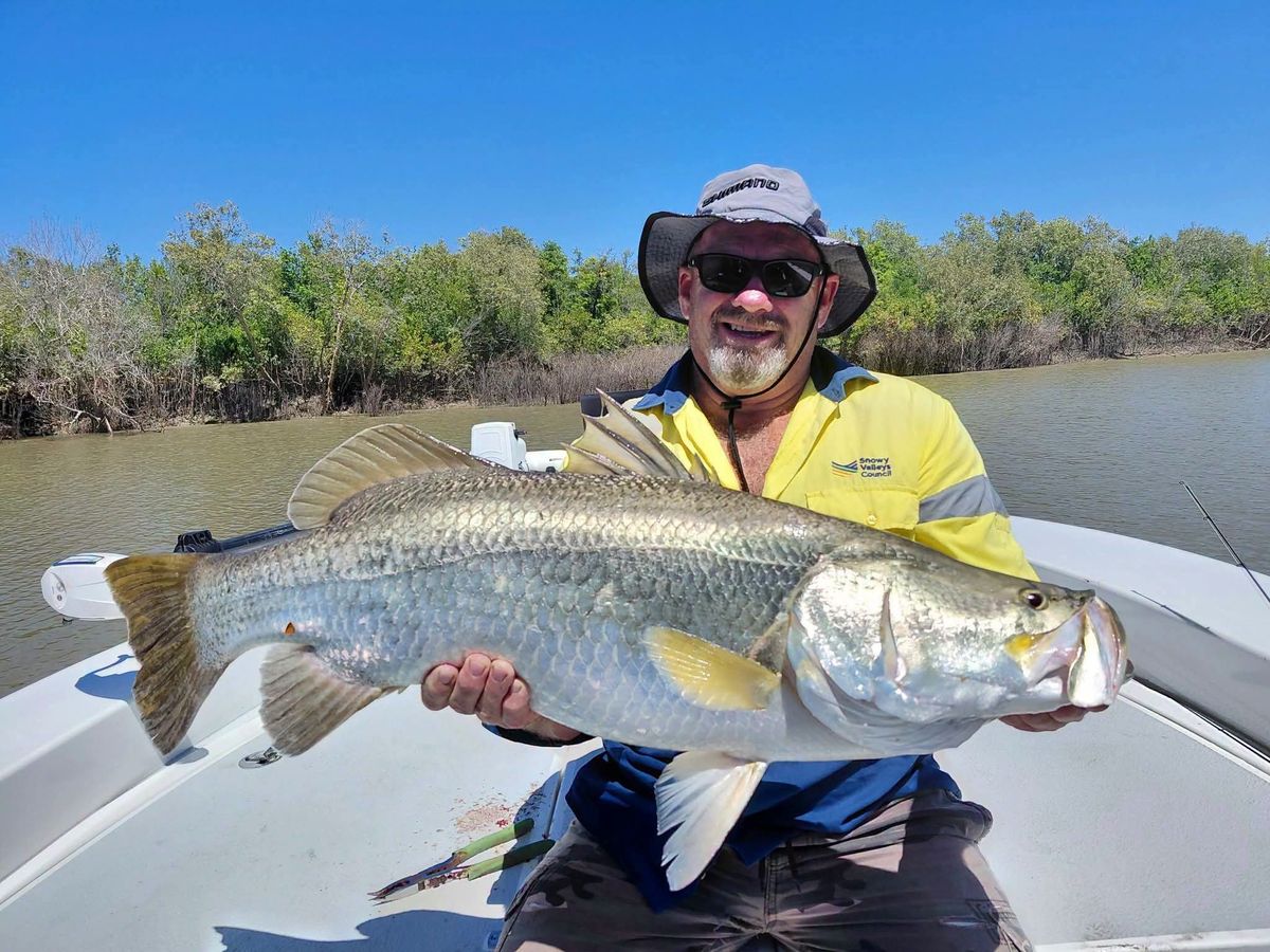Grinning angler with a barramundi in a mangrove creek