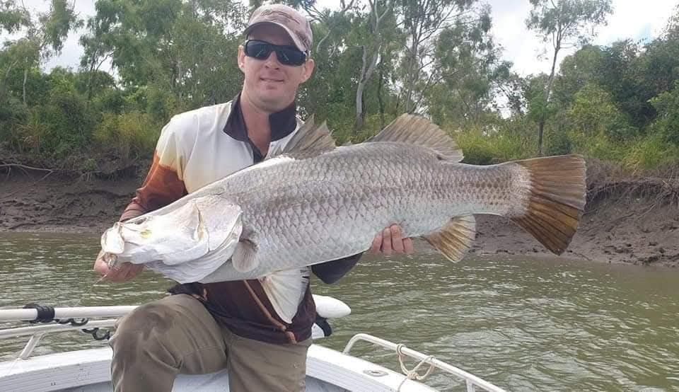Angler with a barramundi on a muddy tidal river