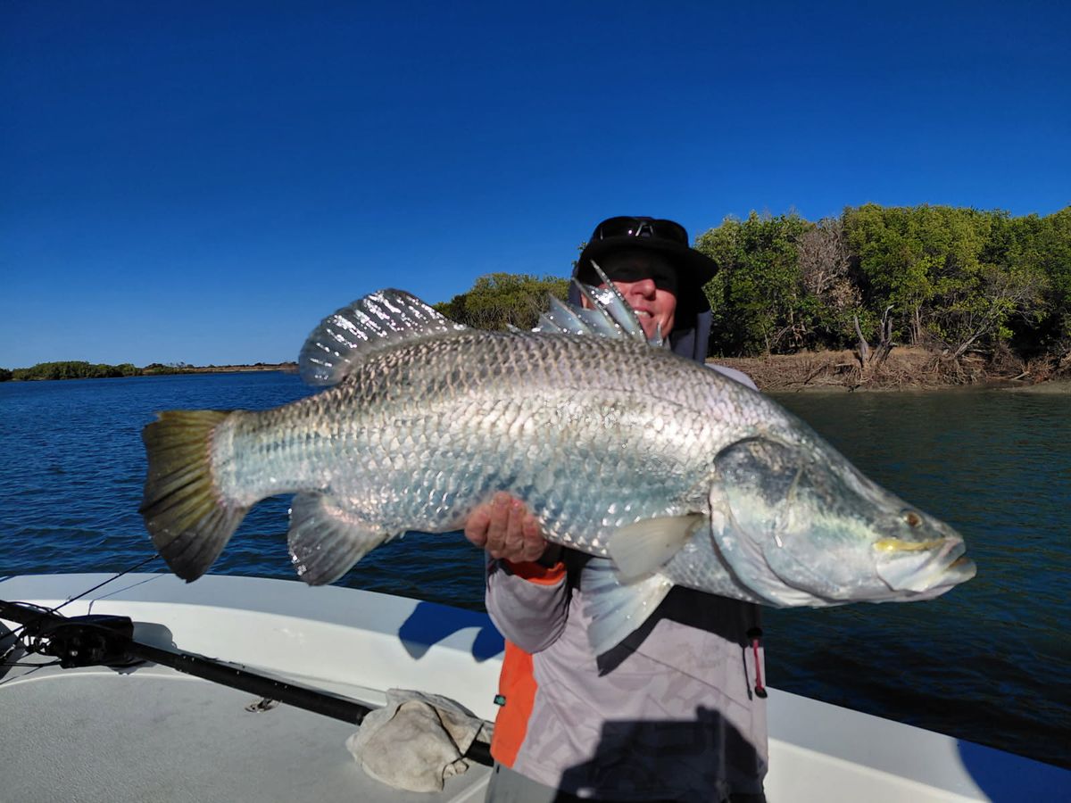 Angler in a wide brim hat with a silver barramundi